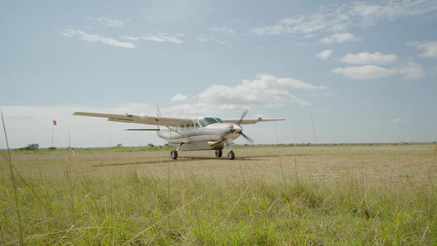 A plan travels down a grass and dirt runway