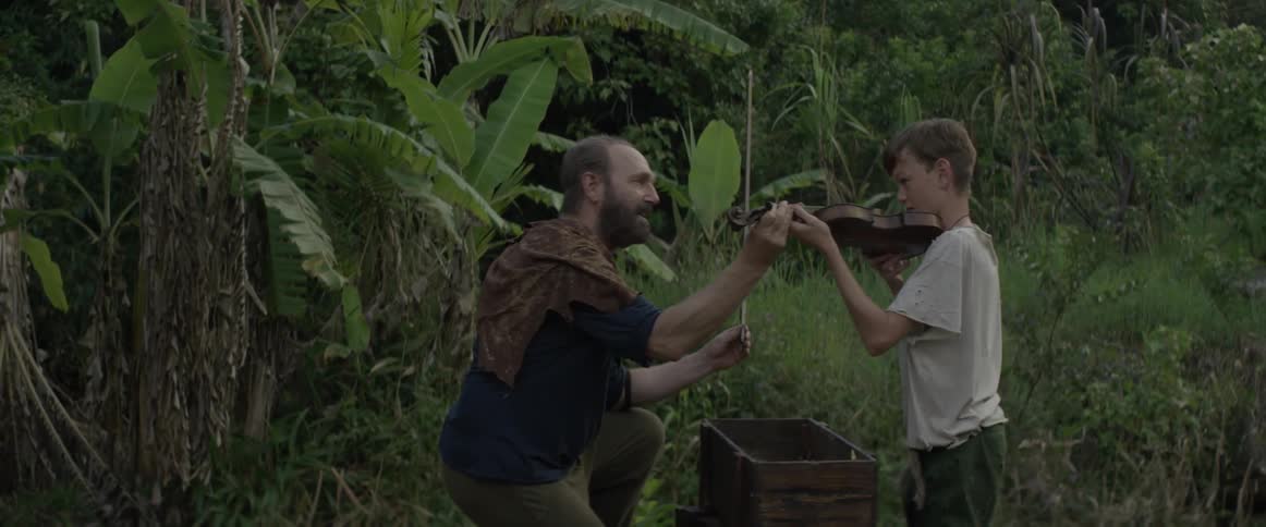 Man helps young boy with violin outside