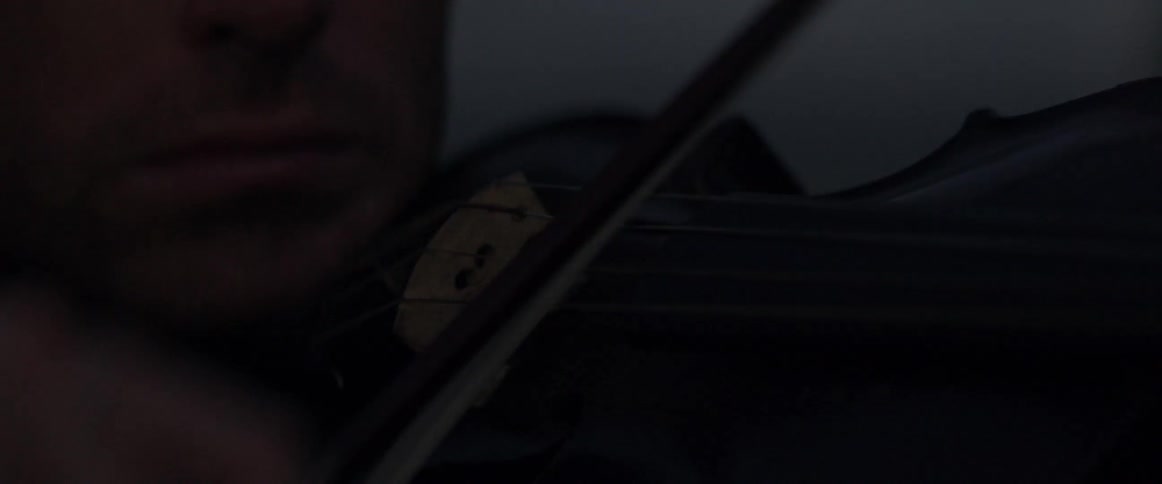 Close up of a bow on a violin in the dark