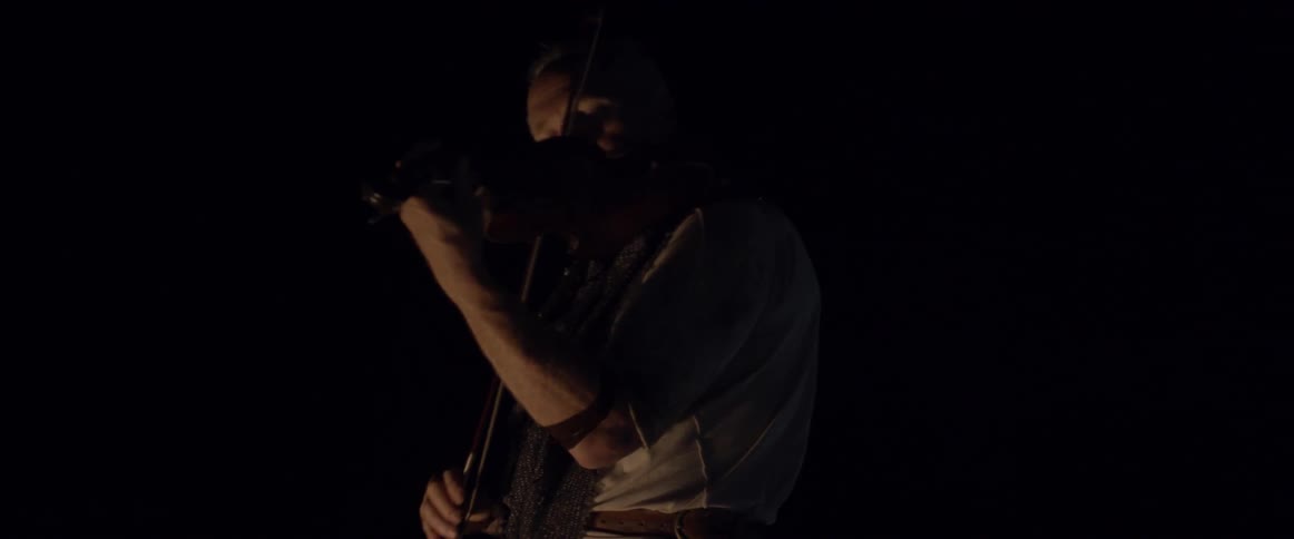 Man plays a violin in dim light