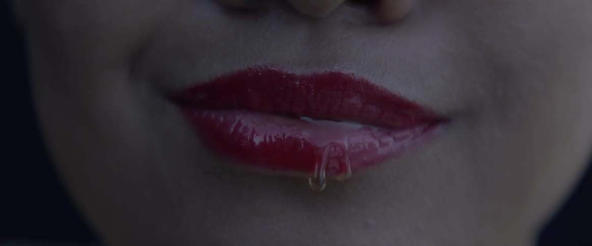 Liquid drips off a bright red lips