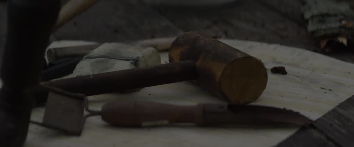 Various tools and implements rest on a wood surface