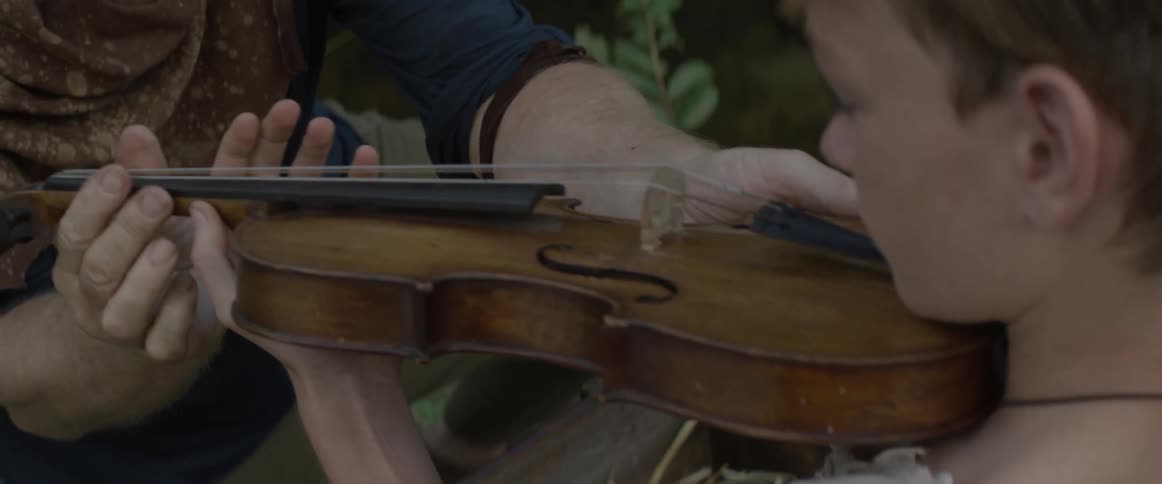 A man hands another a violin