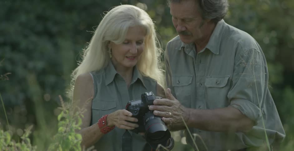A man and woman look at a camera together