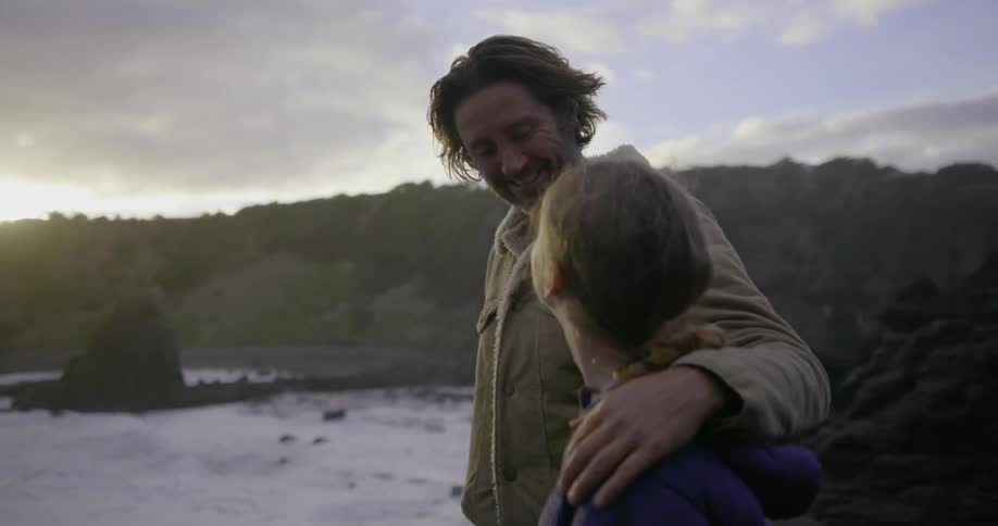 A man and woman are standing next to each other looking out over the ocean at dusk