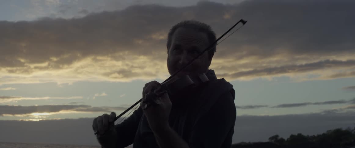 Two violinists play outside at sunset