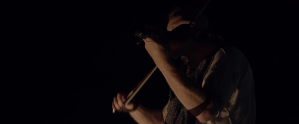 Two men play violin outside at night