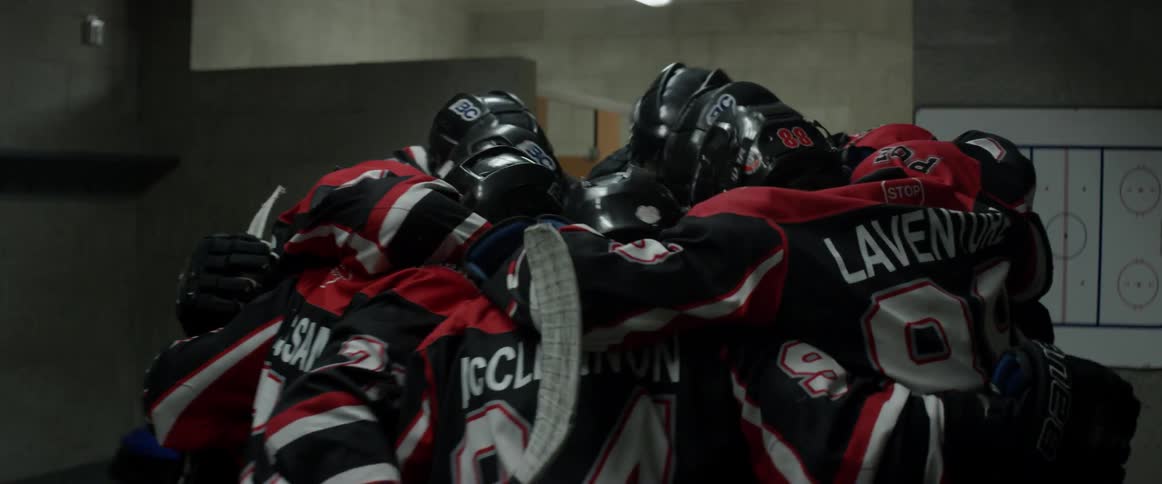 A group of hockey players huddle in the locker room