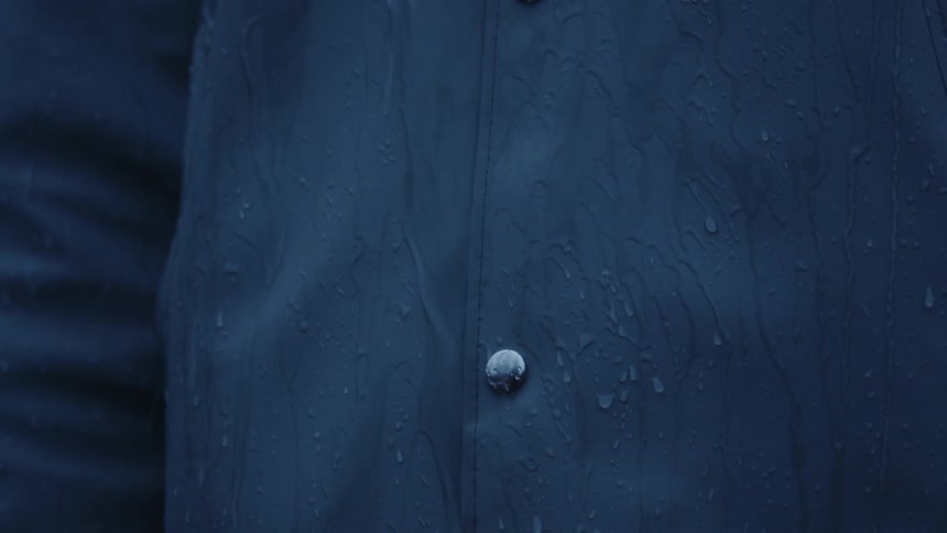 Water streams and drips down a person in a raincoat