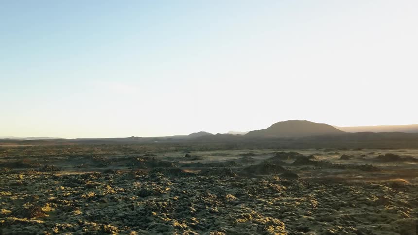 The sun casts harsh light and shadows over an icelandic landscape