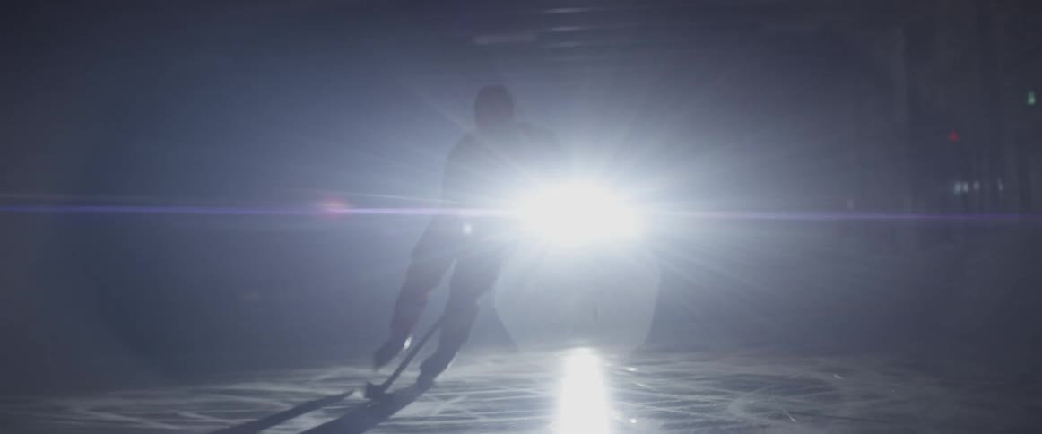 A hockey player charges on skates across the ice
