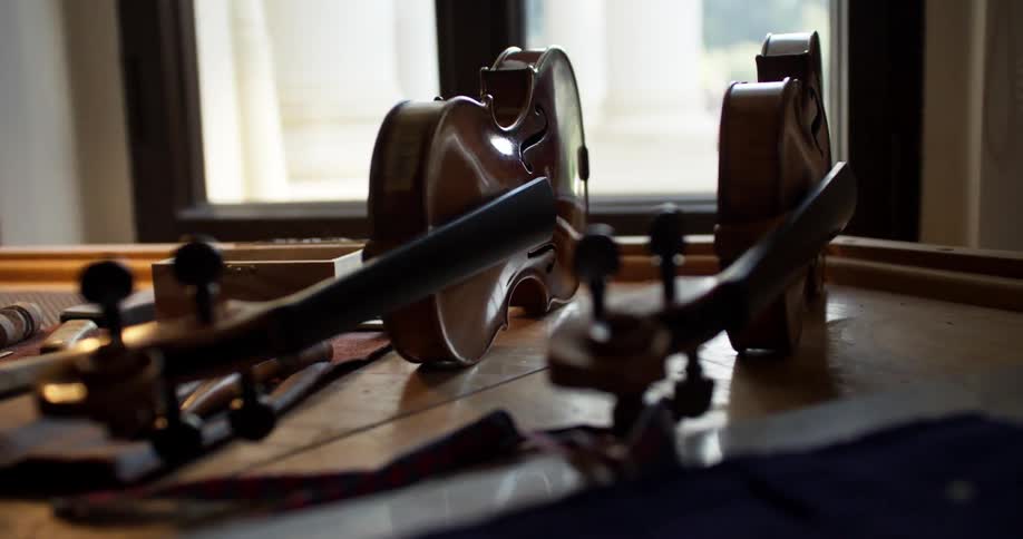 Violins sit next to tools on a workbench
