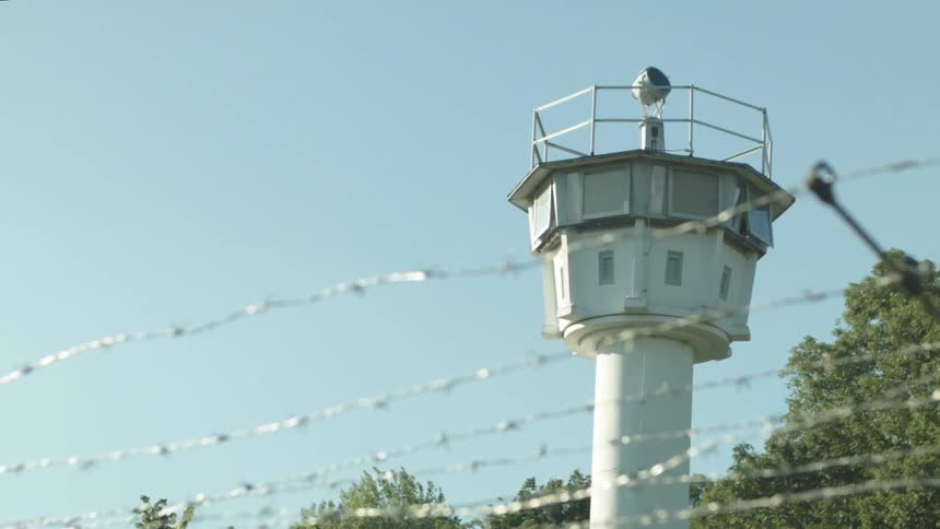 Behind the barbed wire fence is a watchtower
