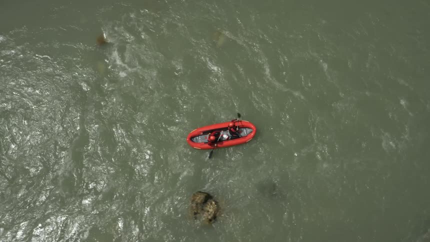 Two people row an inflatable canoe in a river during the day