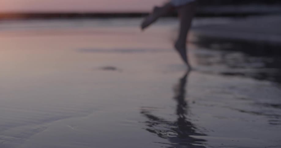 A woman hops on a sandy beach at sunset