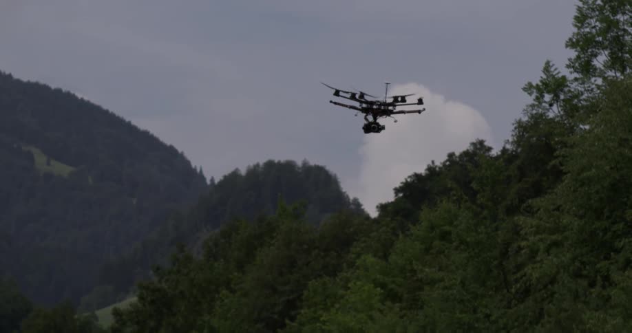 Small drone flies above trees