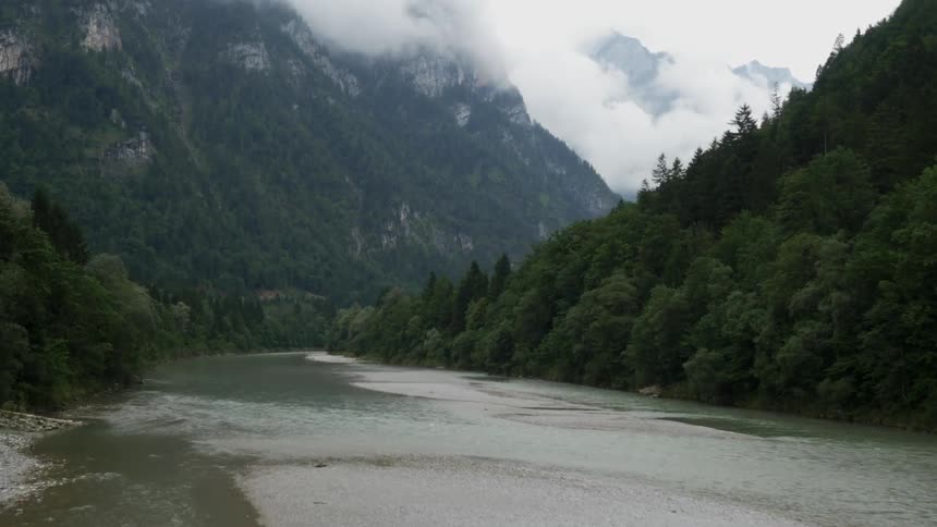 A drone is filming a large stream in between two mountains
