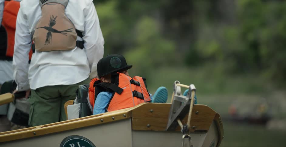 A boy rides in a boat while a man rows