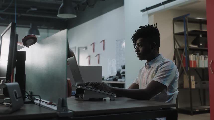 A man is sitting at a computer in an office typing