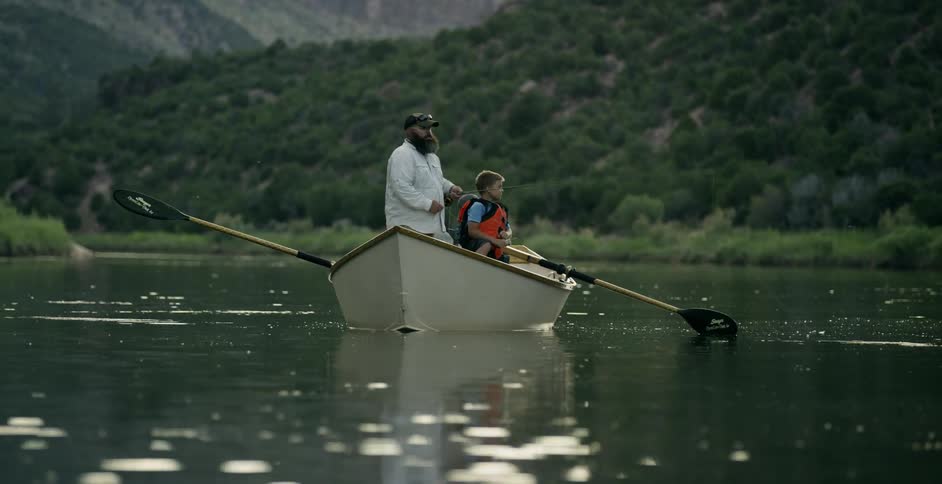 A man and boys fish from a rowboat in a lake