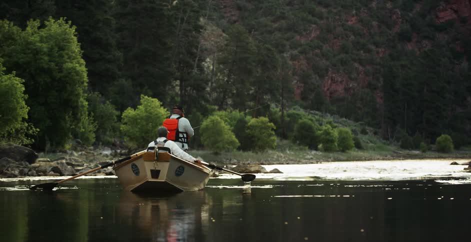 Two men row a boat down the river