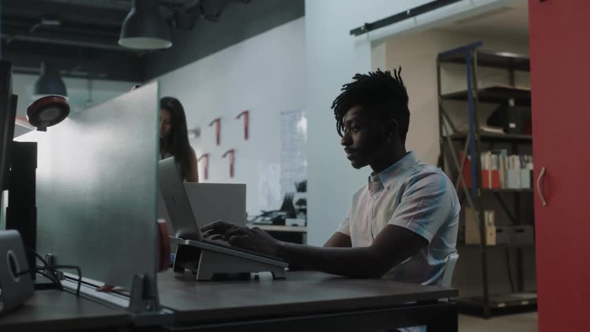 A man is working on a laptop in an office