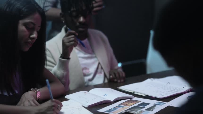 Young people are looking at pictures and discussing them at a conference table