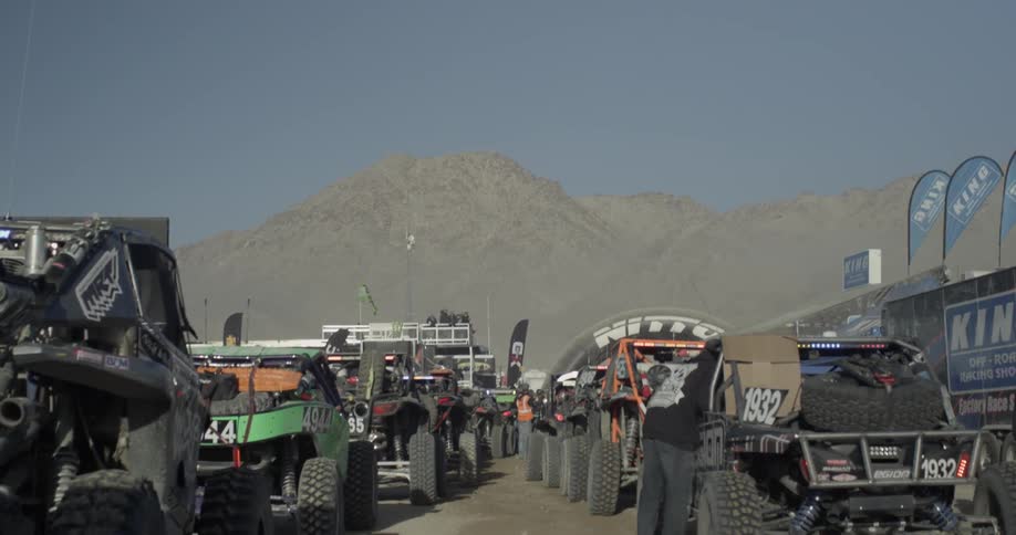 Off road vehicles line up in two rows in the sand