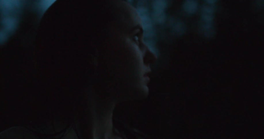 Woman standing outside in the dark near trees