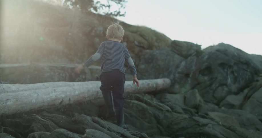 A young boy walks on rocks on a sunny day