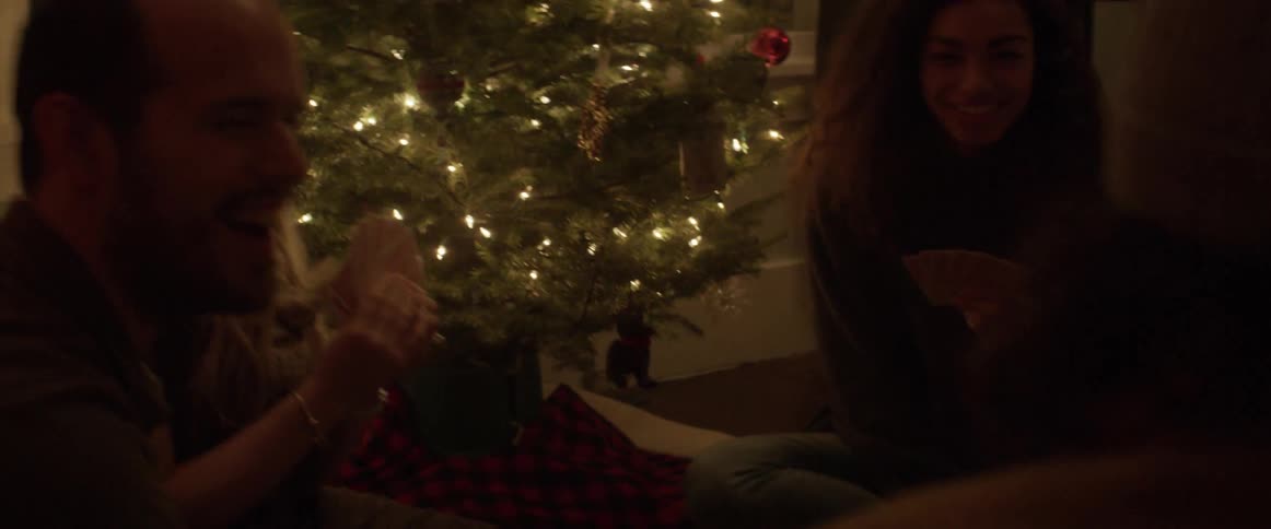 A group of people play cards by the christmas tree