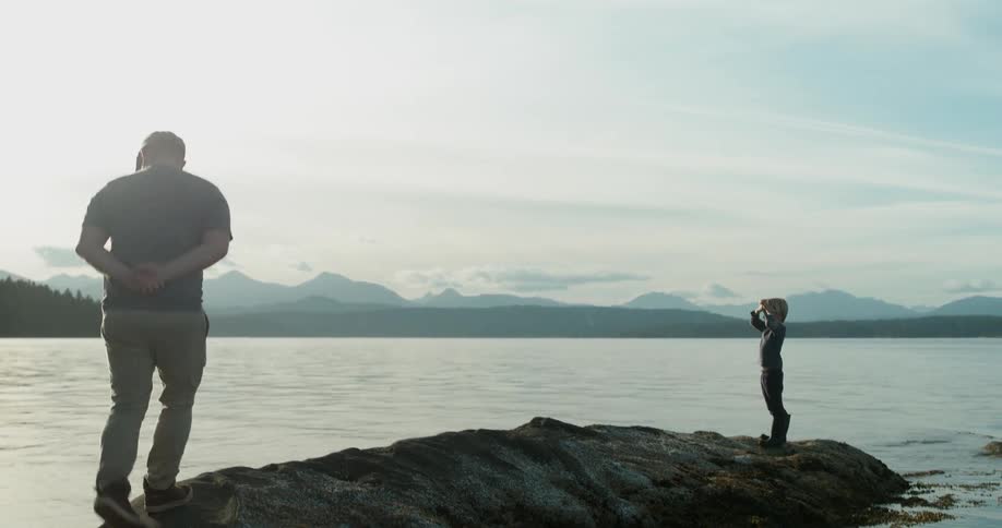 Man and boy stand on a beach rock