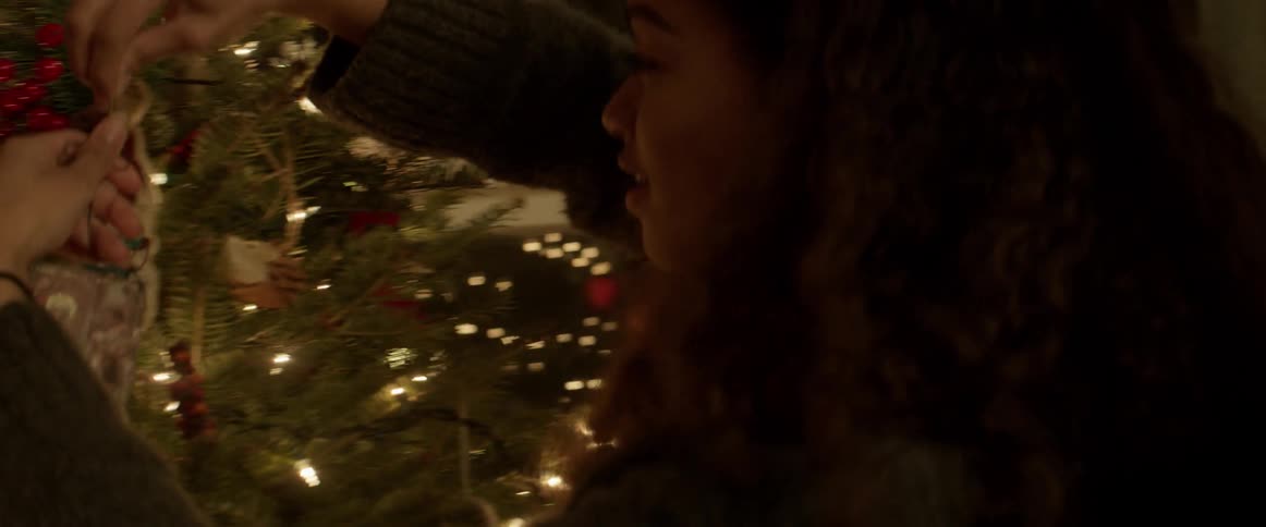 A woman places ornaments on a Christmas tree