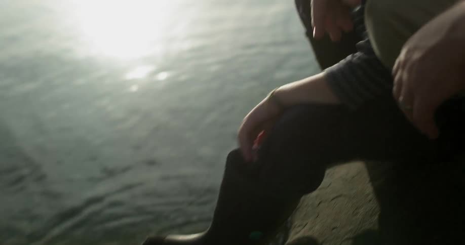 A man sits with his son by the water