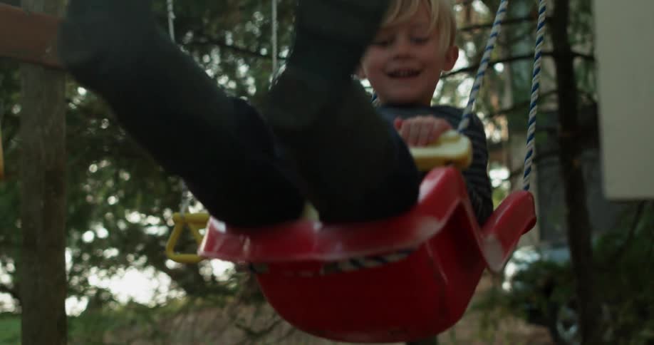 A young boy swings on a swing set