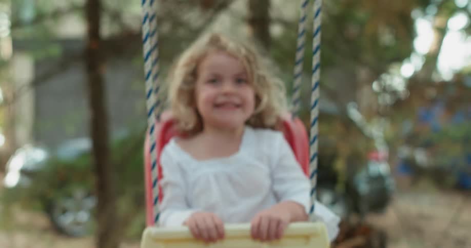Smiling child sits in a swing