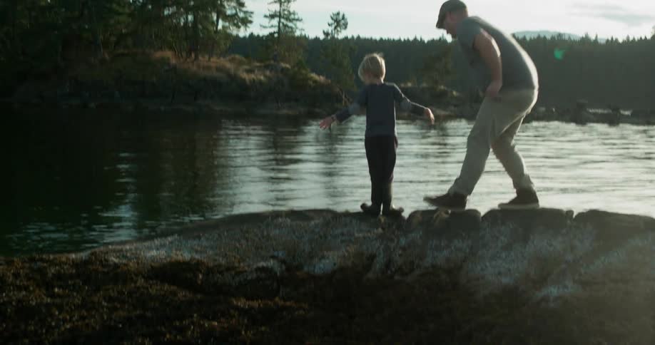 A man and his son stand near the water