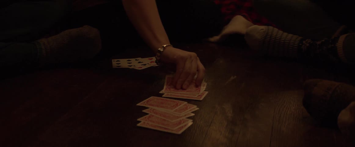 A group of people play cards by the christmas tree