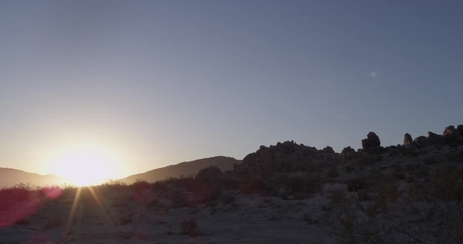 Sun rising over hilly landscape