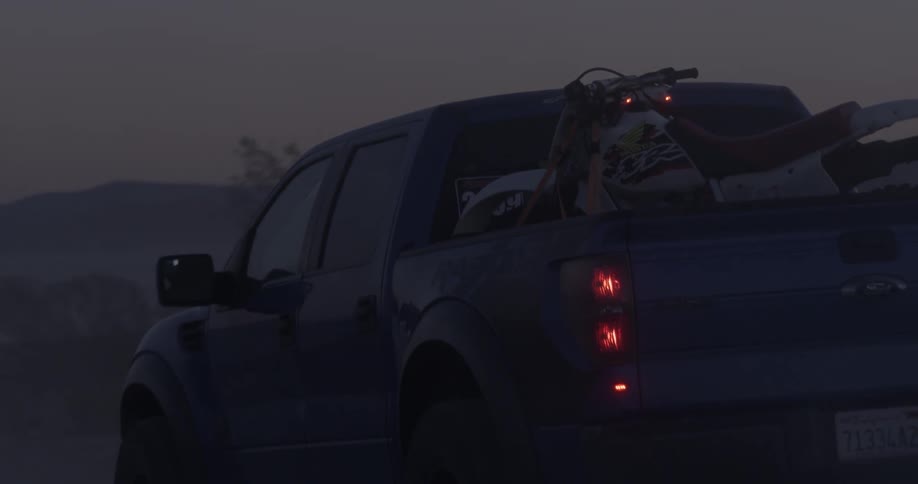 A man drives a truck hauling dirt bikes