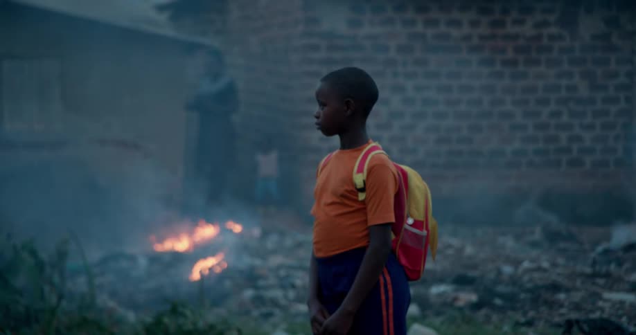 Child standing next to fire burning and smoke outside of a house