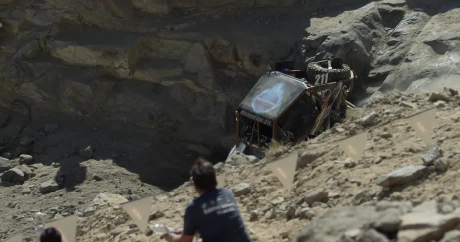 All-terrain vehicle maneuvering an insanely rocky area as people watch from a distance