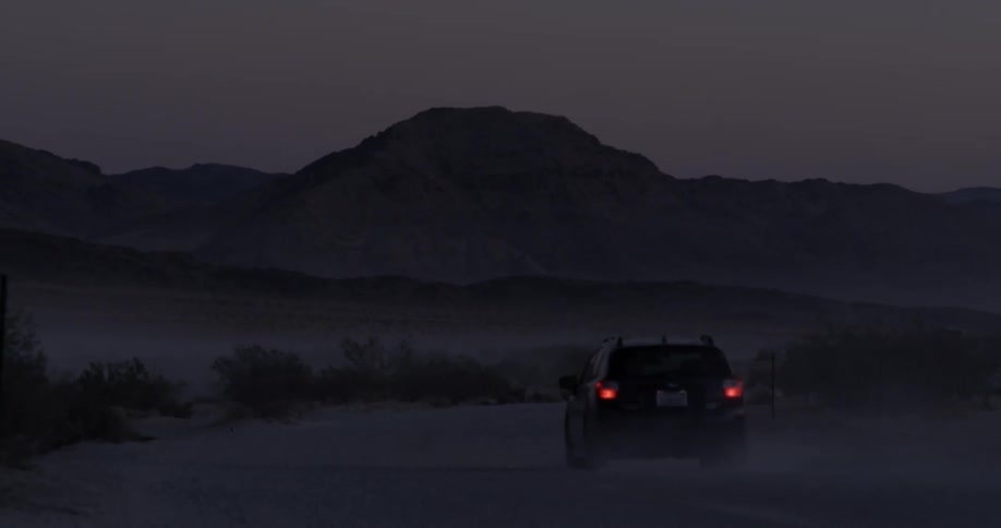 A car travels in the desert at night