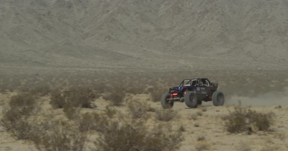 An off road vehicle travels through the desert
