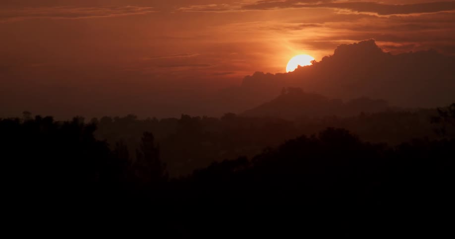 Sun setting behind some clouds on a reddish colorful evening
