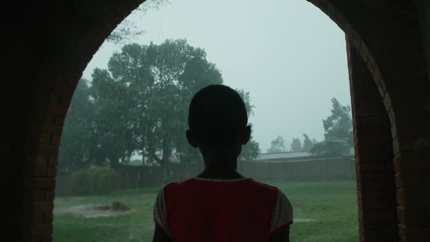A young child stares outside as it rains