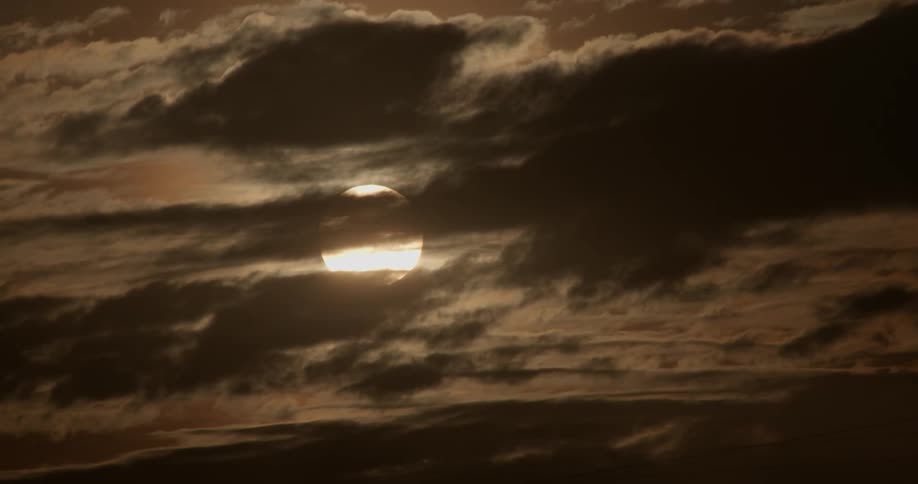 A sun sets behind clouds