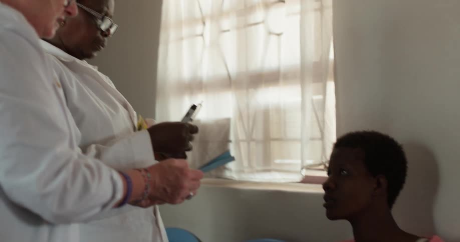 Two medical professionals talk to a woman holding a baby