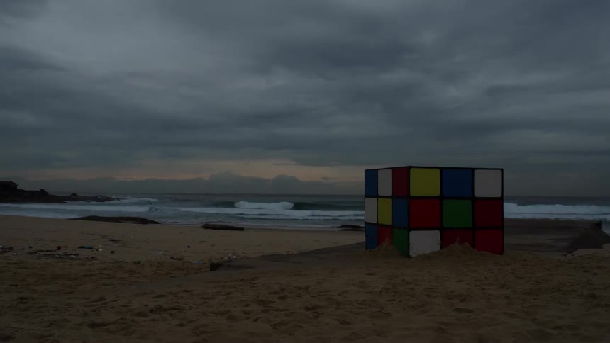 A large rubiks cube on the beach