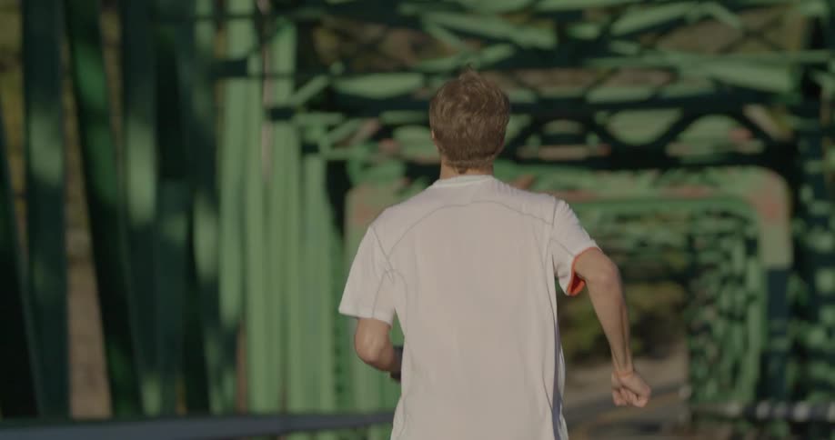 A young man jogs along a trestle bridge